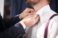 Groomsman helps to groom to put on shirt.