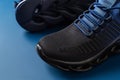 Grooved sole men sneakers of black blue colors on a blue background. Pair of new mesh textile shoes for active lifestyle and