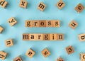 Gross Margin word on wooden block. Flat lay view on blue background