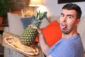 Grossed out man holding pineapple and pizza