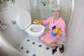 Grossed out senior woman cleaning the toilet