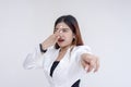 A grossed out young woman pointing the camera while pinching her nose in disgust. Isolated on a white background
