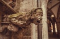 Grotesque carved waking-up human figure projecting from the gutter of a building, Stone gargoyle on building in Bavaria