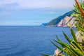 Grotta di Lord Byron with blue water, coast with rock cliff, yellow boat and blue sky near Portovenere town