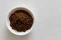 Ground allspice in white ceramic bowl on white wood bac