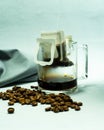 Ground, a bag for coffee drops and a transparent mug on the table. Drop coffee on a gray background with coffee beans. coffee i Royalty Free Stock Photo