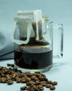 Ground, a bag for coffee drops and a transparent mug on the table. Drop coffee on a gray background with coffee beans. coffee Royalty Free Stock Photo