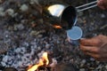 Ground black coffee in a copper Turk is brewed and boils on camp fire.