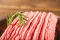 Ground chicken with a sprig of rosemary on a wooden plate on a textural table. Turkey mince raw close-up and copy space Royalty Free Stock Photo