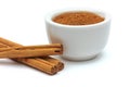 Ground cinnamon in a bowl with cinnamon sticks