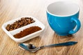 Ground coffee and coffee beans in partitioned bowl, empty coffee cup, spoon on wooden table Royalty Free Stock Photo