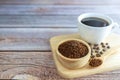 Ground coffee powder in a wooden cup and in a wooden spoon with a white coffee cup and coffee beans all on a wooden tray Royalty Free Stock Photo