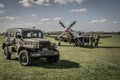 Ground crew maintain a p-51 Mustang with a WW2 military sedan in