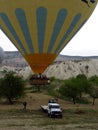 Ground Crew Pulling Down a Landing Yellow and Blue Hot Air Balloon