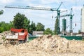 Ground excavation site with heavy tipper trucks and construction cranes on the new residential building terrain preparation, with Royalty Free Stock Photo