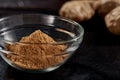 Ground ginger in a plate on a black background. In the background, the root of ginger. side view. sharp powder. macro photo.