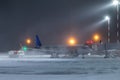 Ground handling of a passenger aircraft at the air bridge in a winter blizzard at night Royalty Free Stock Photo