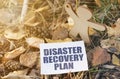 On the ground among the leaves near the wooden figure of a man paper with the inscription - Disaster Recovery Plan Royalty Free Stock Photo