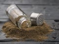 Black pepper is poured from a glass pepper jar on a wooden table. Royalty Free Stock Photo