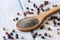 Ground pepper on spoon and colored peppercorns on blue wooden background