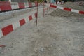 Ground prepared for civil engineering building site bordered by construction barrier planks of red and white color