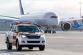 Ground services vehicle - follow me on the apron platform, a large passenger plane is moving behind it