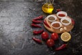 Ground spices for harissa, tomatoes, lemon, oil on a wooden stand on a black background. Copy spaes