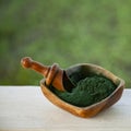 Ground Spirulina in bowl on wood background, top view on dish with superfood