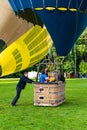 Ground staff man holding the basket with pilot and passengers inside before the launch of hot air balloons at Vingis park in Royalty Free Stock Photo
