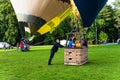 Ground staff man holding the basket with pilot and passengers inside before the launch of hot air balloons at Vingis park in Royalty Free Stock Photo