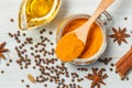 Ground turmeric powder close - up on a wooden spoon, black pepper, vegetable oil, cinnamon sticks and star anise. filled frame