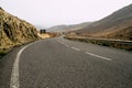 Ground view of a black asphalt long road - concept of travel and search of destination - valley and mountains landscape beautiful Royalty Free Stock Photo