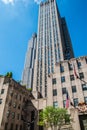 Ground view looking up at a large New York City skyscraper. The statue of Atlas is at the base of this Rockefeller Plaza building