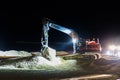 Ground worker working at nighttime in the dark with a digger machine moving the sand at the beach for maintenance Royalty Free Stock Photo