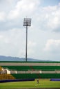 A groundskeeper tends to the lush green turf at a vibrant soccer stadium, adorned with colorful spectator seats