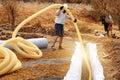 A worker carries a yellow perforated drainage pipe. Groundwater drainage works in the field