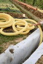 A worker carries a yellow perforated drainage pipe. Groundwater drainage works in the field