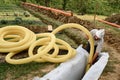 A worker carries a yellow perforated drainage pipe. Groundwater drainage works in the field