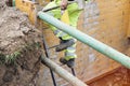 Groundworker builder using steps ladder to get out of deep drainage eaxcavation trench support box. Builder going up using