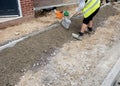 Groundworker placing and levelling with the shovel a semi-dry concrete around edging kerb during footpath construction Royalty Free Stock Photo
