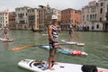 Group of active tourists stand up paddling on sup boards at Grand Canal, Venice, Italy.