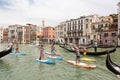 Group of active tourists stand up paddling on sup boards at Grand Canal, Venice, Italy.