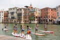 Group of active tourists stand up paddling on sup boards at Grand Canal, Venice, Italy.