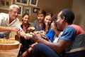 Group of adult friends eating pizza at a house party Royalty Free Stock Photo