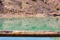 group of adult people with colorful backpack trekking on a path of sand and stones walking next to a lake reflecting their images