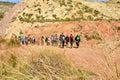 group of adult people with colorful backpack trekking on a path of sand and stones walking to mountain with a amazing landscape on