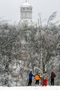 Group of adult people wearing colorful sportive clothers standing on background of forest and church. Skiing at winter park.