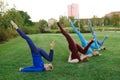 A group of adult women attending yoga outside in the park