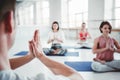 Group of adult women and man doing yoga exercises together in fitness class. Active people practice yoga poses on mat. Health care