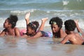 Group African kids in swimsuit have fun together on beach, boys and girls with black curly hair lying down in line at tropical sea Royalty Free Stock Photo